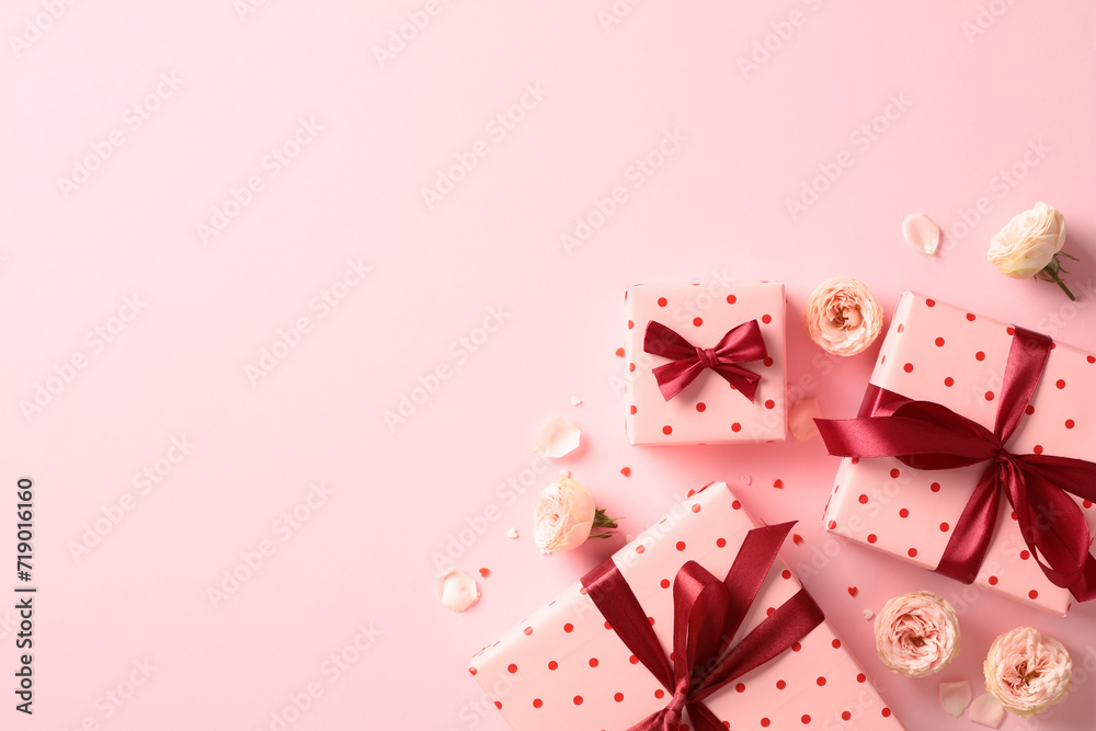 Saint Valentine day holiday background with pink gift boxes with red ribbon bow, roses buds, confetti on pastel pink background. Flat lay composition. Top view.