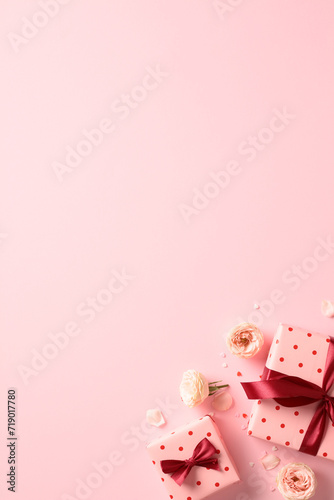 Valentine's Day vertical pink background with gift boxes and roses buds. Flat lay, top view.