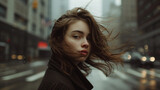 Portrait of a young girl on the street of a cold city. Windy weather. Dramatic composition.