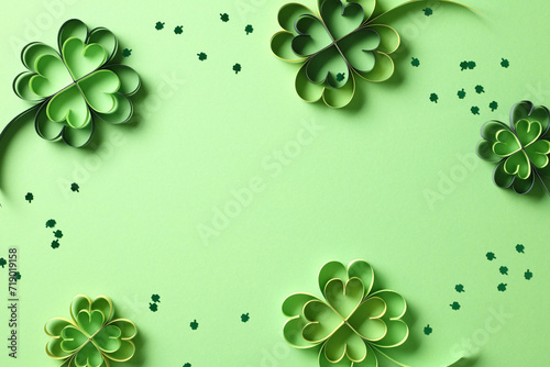 Paper art and craft style four-leaf clover and confetti on green background. St Patrick's Day holiday concept.