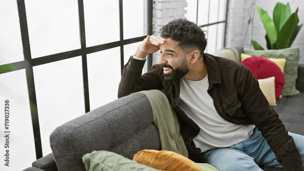 At home, a cheerful young man, smiling confidently, hand held high, searching the distance. his eyes look far away, his happiness filling the room. At home, a cheerful young man, smiling confidently, hand held high, searching the distance. his eyes look far away, his happiness filling the room.