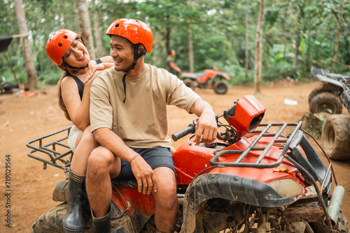 beautiful asian women looking at the asian man while sitting on atv together