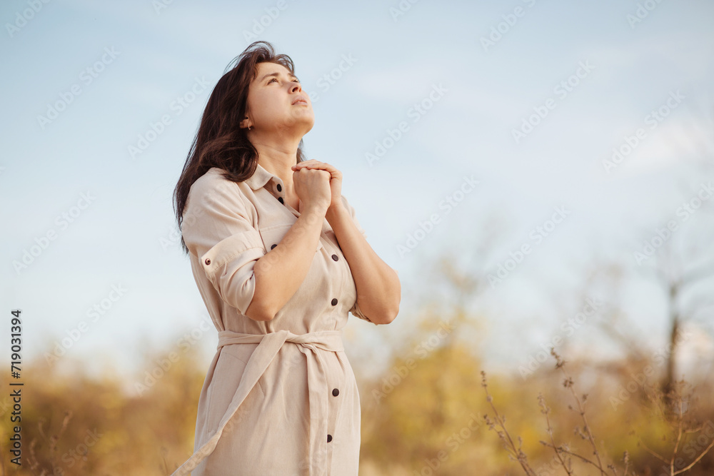 portrait of young woman praying on nature, girl thanks God with her hands folded under chin, concept of religion portrait of young woman praying on nature, girl thanks God with her hands folded under chin, concept of religion