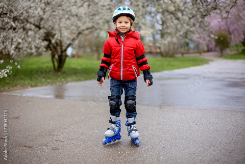 Little child, preschool boy in protective equipment and rollers blades, riding on walkway
