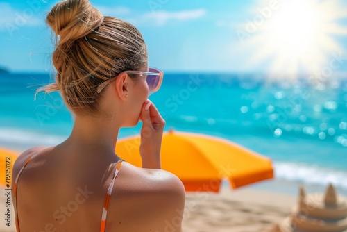 A woman applying sunscreen on her shoulders, on a sunny beach, crystal clear blue sea in the background, woman centered, bright and warm sunlight, beach umbrella 