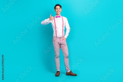 Full body photo of optimistic guy wear white shirt pink bow tie showing thumb up approve birthday party isolated on blue color background © deagreez