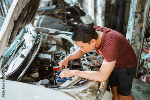 A male mechanic checks a car battery at a service station