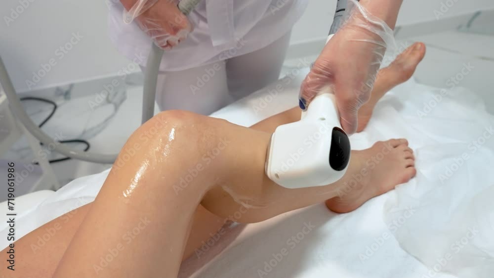 Laser hair removal technology in contemporary beauty clinic, cosmetologist using apparatus on skin of slim woman legs close up. Female body care, smooth skin after epilation, medicine and well being