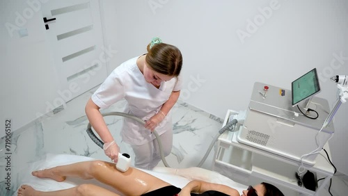 Woman beautician removes hair on beautiful female skin using safe depilation laser at hospital room. Laser hair removal procedure in epilation beauty medical spa clinic photo