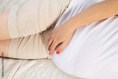 a pregnant girl lies on the bed and holds her stomach. Concept of cystitis and inflammation of the urinary tract and bladder in pregnant women.