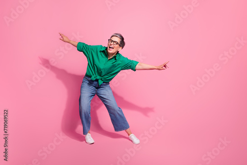 Full body photo of attractive pensioner woman dance energetic moving party dressed stylish green clothes isolated on pink color background