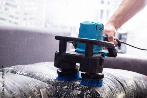 Dry cleaning of the sofa with a special electric brush to raise the pile, close-up. photo