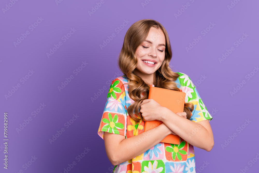 Portrait of satisfied nice girl with curly hairdo dressed print t-shirt embrace book eyes closed isolated on violet color background Portrait of satisfied nice girl with curly hairdo dressed print t-shirt embrace book eyes closed isolated on violet color background