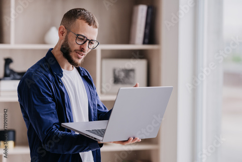 Focused man with glasses working on laptop in a stylish home office space