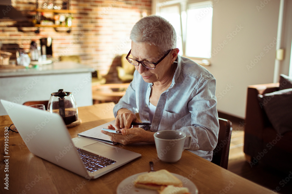 Senior woman working from home and taking notes Senior woman working from home and taking notes