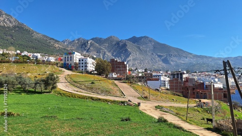 Bright spring view with a Breathtaking Landscape: Nestled Between Majestic Mountains and Lush Greenery, Quaint Town with Colorful Buildings Under the Clear Blue Sky, chefchaouen Morocco © ayman