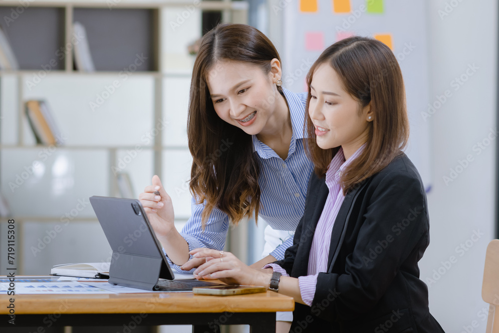 Happy two asian businesswoman working with tablet in meeting room, Businesswoman standing and talking about ideas in office workplace. Happy two asian businesswoman working with tablet in meeting room, Businesswoman standing and talking about ideas in office workplace.