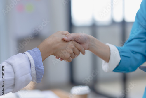 Happy two asian businesswoman making handshake with partner in meeting room, Businesswoman standing and talking about ideas in office workplace.