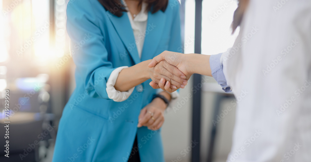 Happy two asian businesswoman making handshake with partner in meeting room, Businesswoman standing and talking about ideas in office workplace. Happy two asian businesswoman making handshake with partner in meeting room, Businesswoman standing and talking about ideas in office workplace.