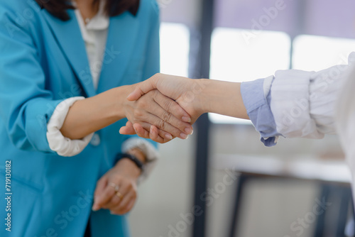 Happy two asian businesswoman making handshake with partner in meeting room, Businesswoman standing and talking about ideas in office workplace. © SOMKID