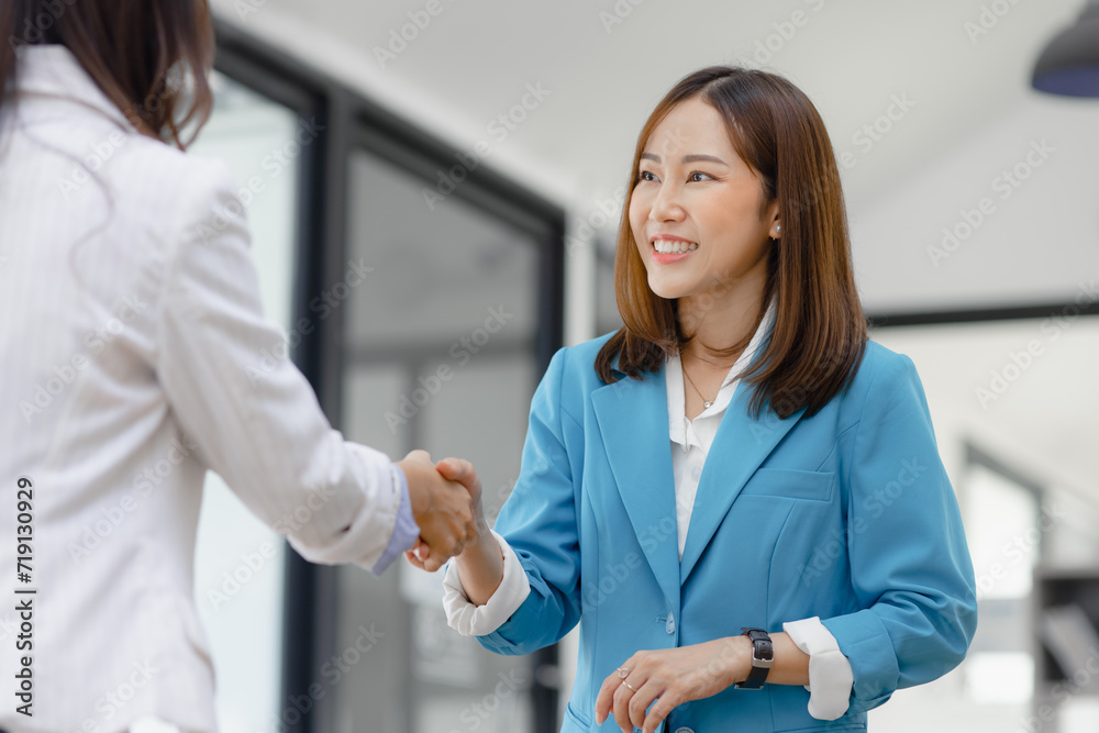 Fototapeta premium Happy two asian businesswoman making handshake with partner in meeting room, Businesswoman standing and talking about ideas in office workplace.