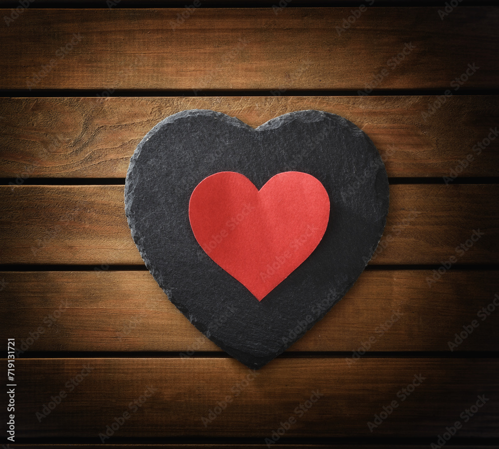Heart cutout on heart-shaped slate plate on wooden slatted table Heart cutout on heart-shaped slate plate on wooden slatted table