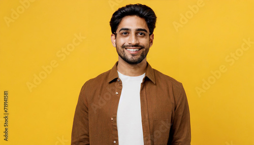 Young smiling happy cheerful fun satisfied cool calm brunet Indian man he wears shirt casual clothes looking camera isolated on plain yellow color wall background studio portrait. Lifestyle concept