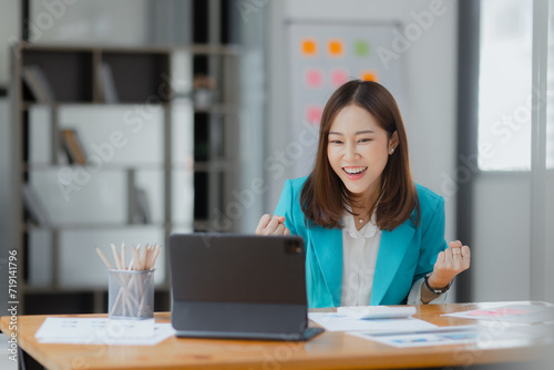 Happy excited asian businesswoman working with tablet computer at office desk, Happy young woman overjoyed.