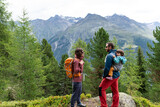 Mother and father with his little daughter in a baby carrier at his back during a hiking day in Austrian Alps.