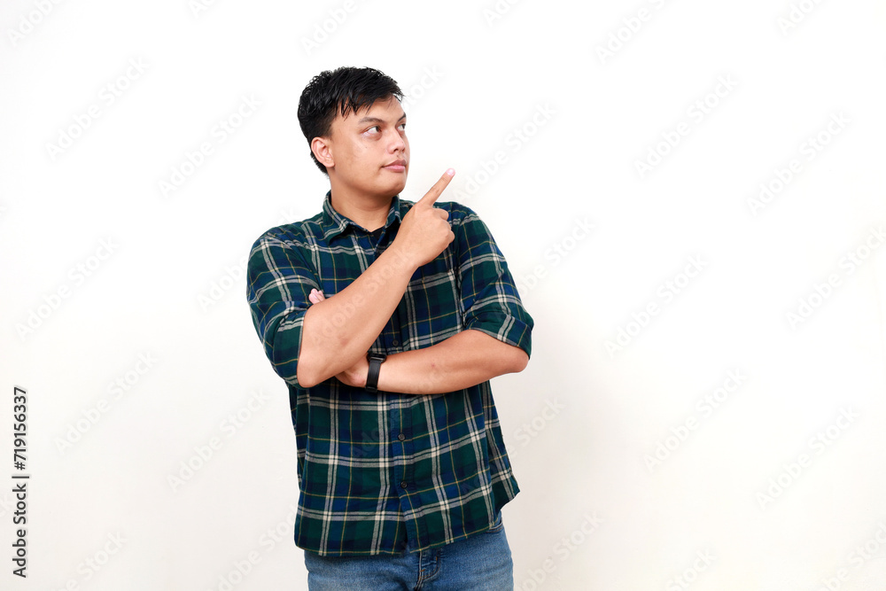 Young adult asian man standing while pointing and looking to the side Young adult asian man standing while pointing and looking to the side