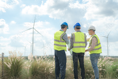 Asian engineer working in fieldwork outdoor. Workers check and inspect construction and machine around building project site. Wind turbine for electrical of clean energy and environment sustainable.