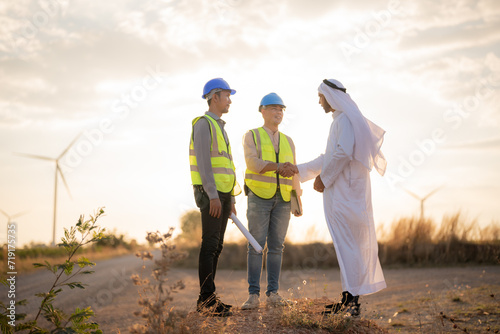 Asian Engineers and Arab businessman checking and inspecting on construction with sunset sky. people operation. Wind turbine for electrical of clean energy and environment. Industrial of sustainable. © ultramansk