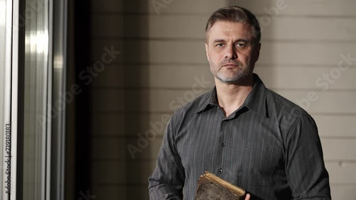 Pastor Reads Bible in Preparation for Sermon. Adult man is holding the Bible in his hands. He is looking at the camera. Searching of God