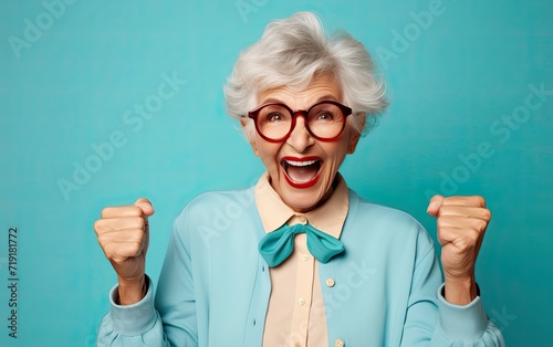 Funny elderly woman with silly expression makes gestures  happily and feels proud of her success  smiles gladfully