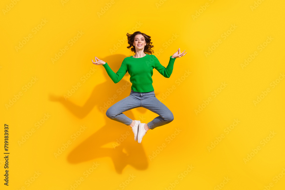 Full body length photo of relaxed woman in sweater denim jeans jumping peace practicing meditation isolated on yellow color background
