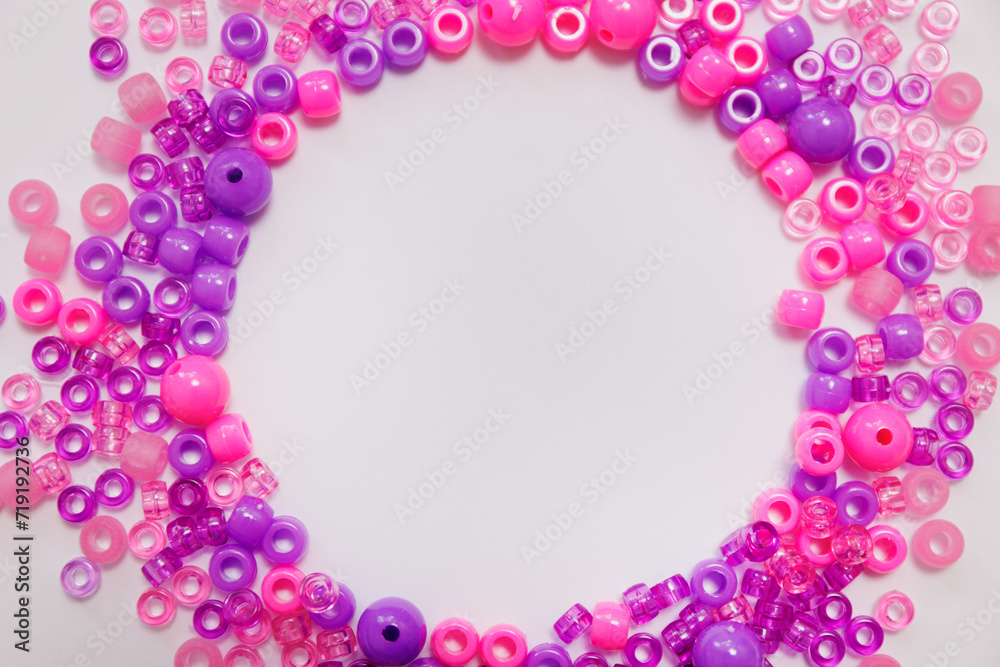 Fototapeta premium Pink and purple plastic beads frame on white background