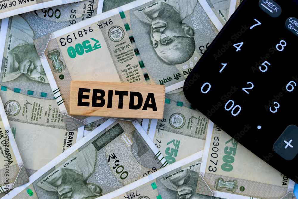 Fototapeta premium EBITDA text on wooden cube with calculation and currency