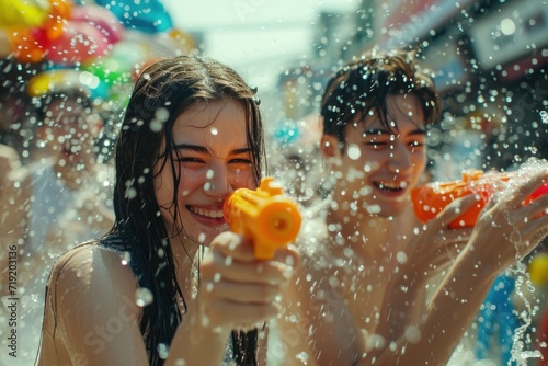 A beautiful Asian female tourist Playing in the water on Songkran Celebrate Songkran Festival Holding a colorful water gun with a fun water play on a street background in Thailand.