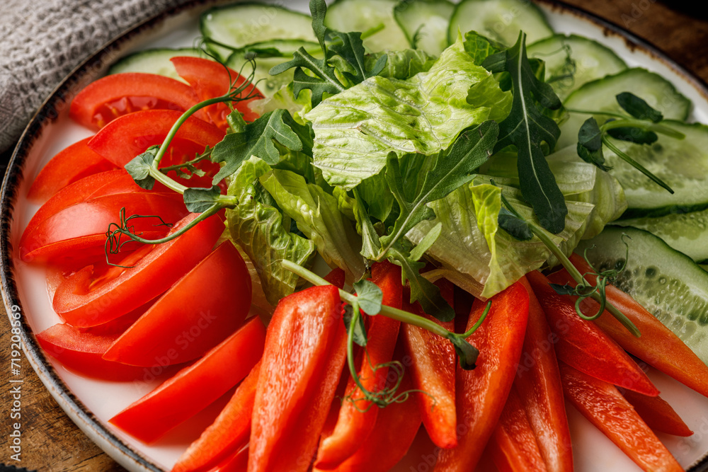 Fresh salad with tomatoes, cucumbers and arugula on wooden table Fresh salad with tomatoes, cucumbers and arugula on wooden table
