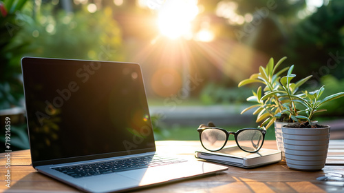 Ein Laptop oder Notebook steht auf einem Tisch im Freien, Garten oder Park und eine Brille liegt daneben wahrscheinlich home office