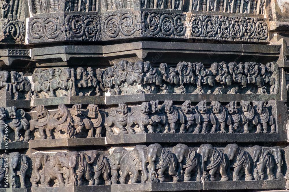 Intricate carvings of a line of elephants, lions and an army of horses on the wall of the ancient Chennakashava temple in Belur in Karnataka.
