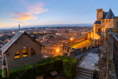 Sunset view overlooking the city and village from inside the medieval fortress and illuminated castle walls of La Cité in Carcassonne, France.