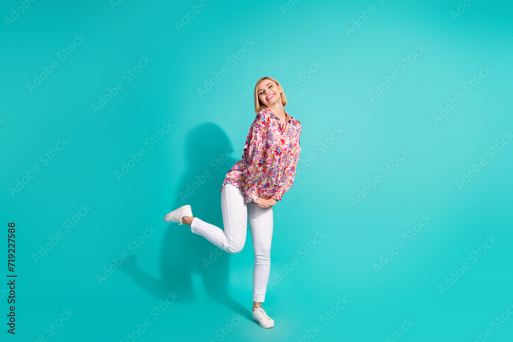 Full size photo of lovely nice pretty girl wear oversize shirt white trousers stand on one leg isolated on turquoise color background Full size photo of lovely nice pretty girl wear oversize shirt white trousers stand on one leg isolated on turquoise color background