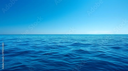 Deep blue ocean waves panorama with sun reflection, clear sky.