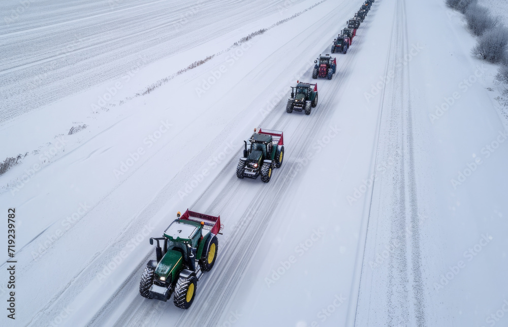 Row of tractors drives along the road, surrounded by snow-covered fields. View from above. Agricultural workers go to protest rally against tax increases, changes in law, abolition of benefits
