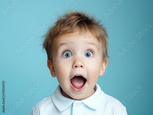 Surprised little boy in a white shirt on a blue background