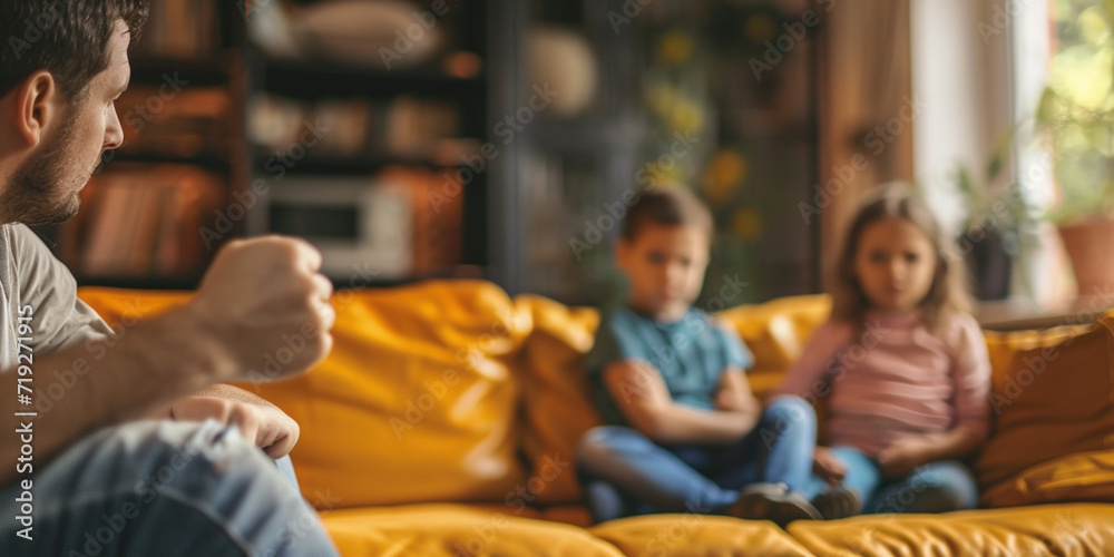 Man threatening kid daughter with his fist. Scared child sitting together on sofa couch in scare. Selective Focus on male hand. Child abuse anger and domestic violence concept.