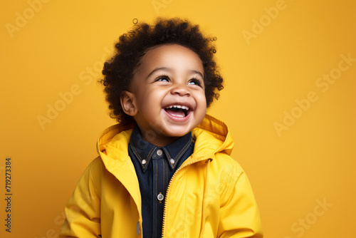African boy laughing cheerfully on yellow background