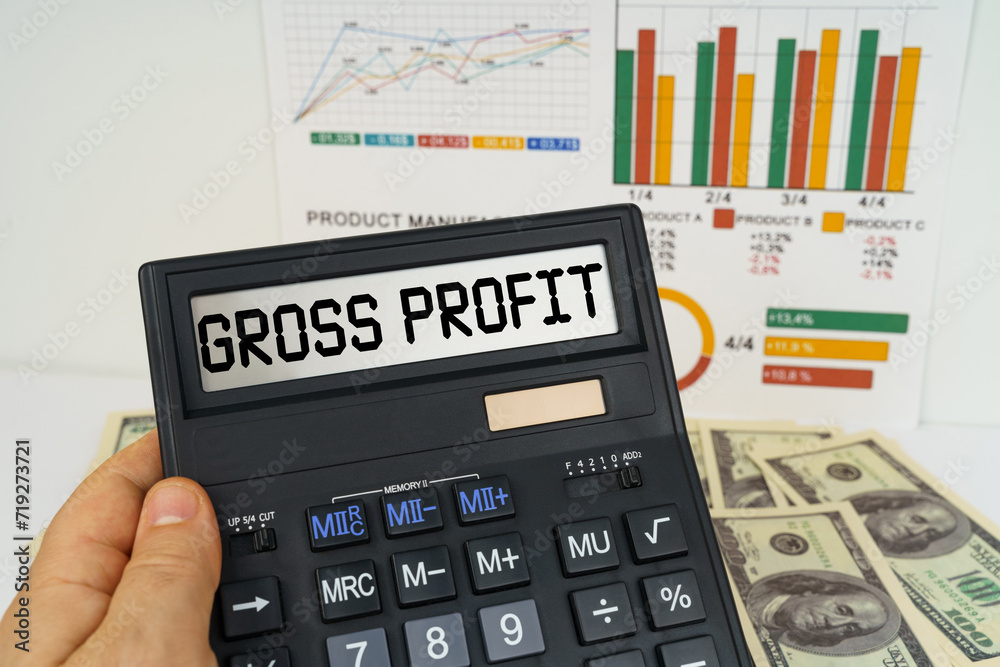 On the table there are financial reports, dollars, in the hands of a calculator with the inscription - gross profit On the table there are financial reports, dollars, in the hands of a calculator with the inscription - gross profit