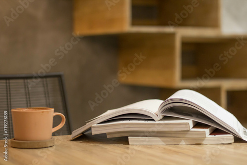 Close up stack of magazine or books with cup of coffee on wooden table in copy space concept. 